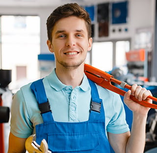 A man in overalls with a wrench, illustrating Titan Exteriors and his role in home improvement and repairs.