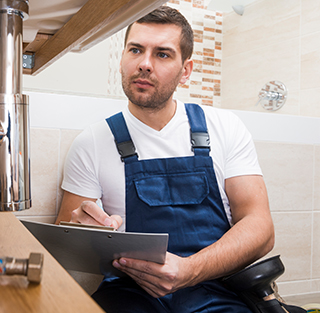 A man wearing overalls is seated on the floor with a clipboard, associated with Titan Exteriors.