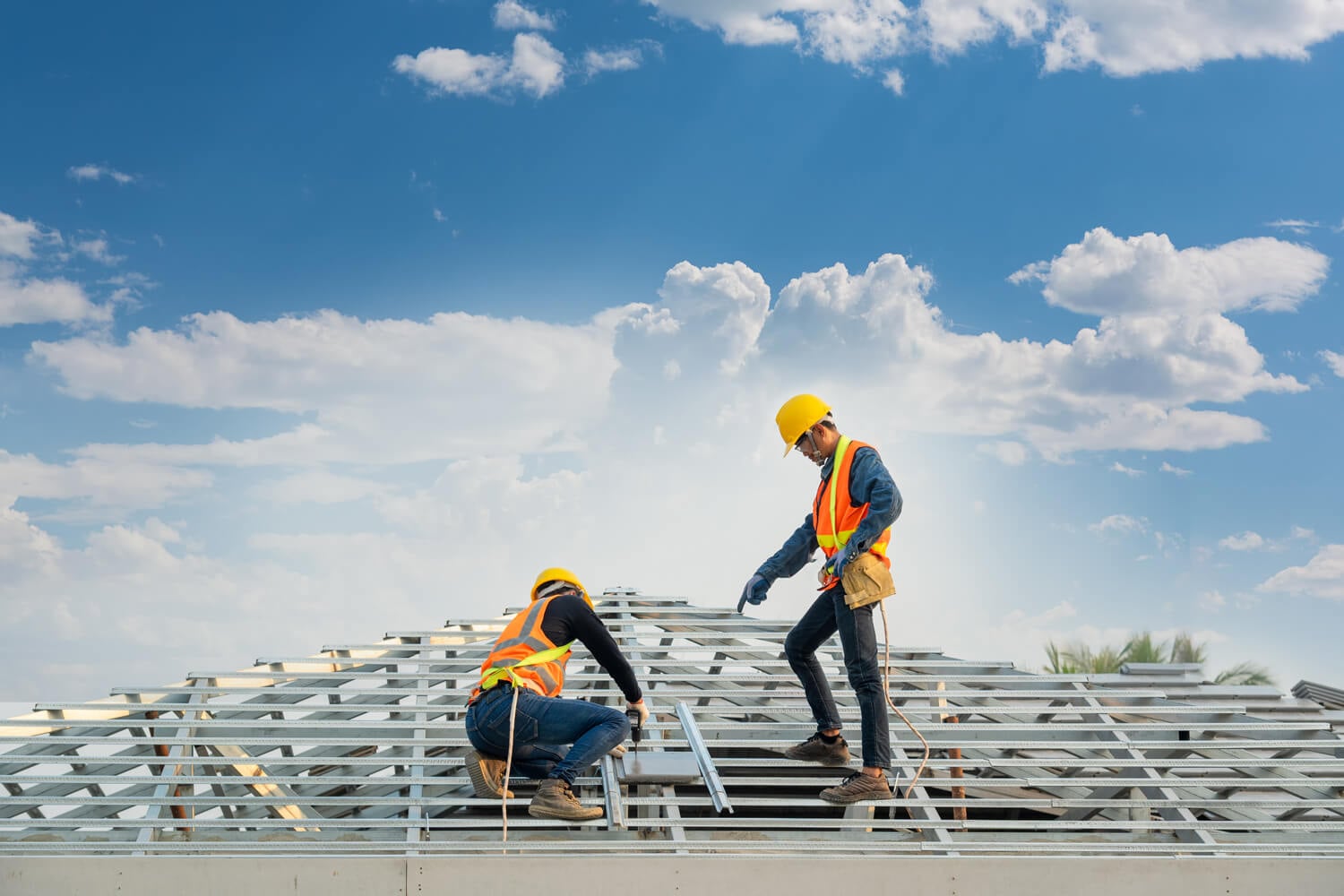 Two men in safety vests working on a roof, representing Titan Exteriors' commitment to safe construction practices.