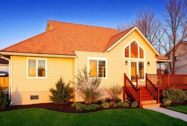A house with a red roof sits on lush green grass, showcasing Titan Exteriors' design and landscaping. A house with a red roof sits on lush green grass, showcasing Titan Exteriors' design and landscaping.